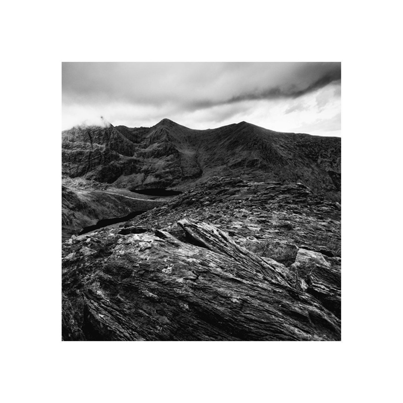 Stuck Between a Rock and a Hard Place 01, a black-and-white mountain landscape under heavy clouds.
